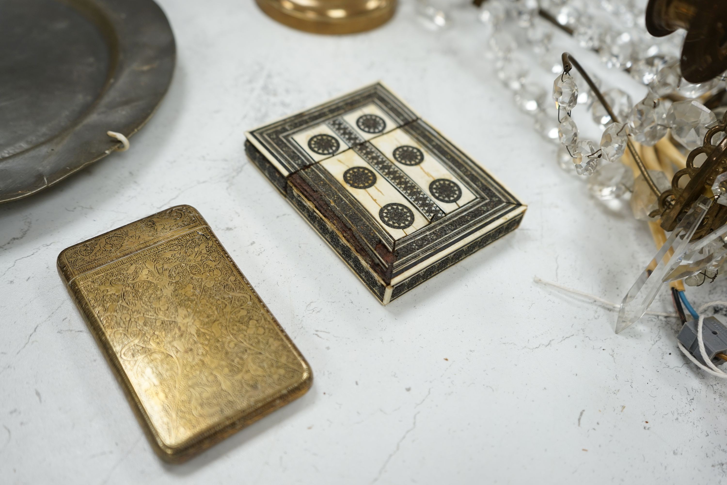 An embossed brass lamp, lustre drop wall light, a pair of bell-metal candlesticks, an 18th century pewter plate and a large Swedish embossed plaque